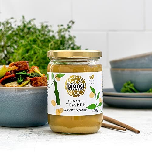 Ein Glas Biona Organic Tempeh neben einem Teller mit Gemüse.