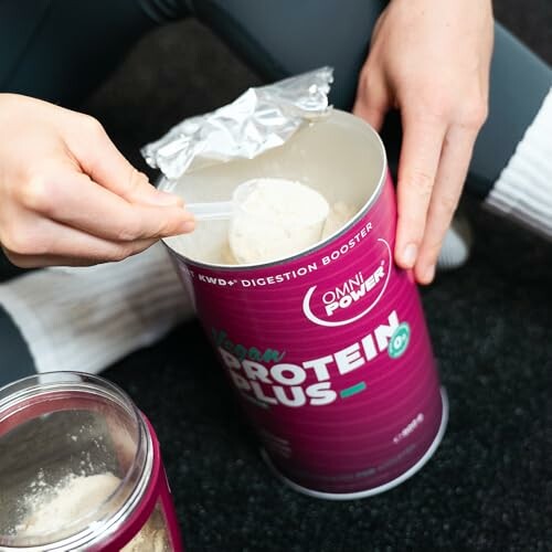 Person schöpft Proteinpulver aus Behälter.